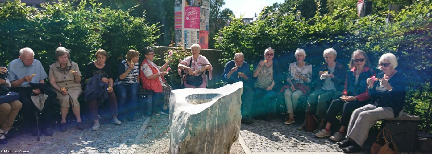 Phänologischer Garten mit Taufstein und Teilnehmer am Cafe am Montag