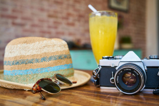 Sonnenhut, Sonnenbrille, Orangensaft, Kamera auf Tisch
